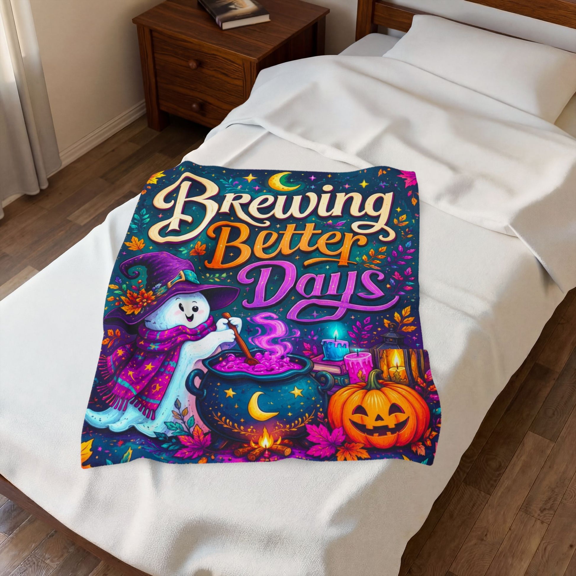 A colorful Halloween-themed blanket spread across a white bed in a bedroom. The blanket features the phrase 'Brewing Better Days' in stylized lettering above an illustration of a ghost in a witch hat stirring a cauldron, with a pumpkin, candles, and stars on a dark blue background.
