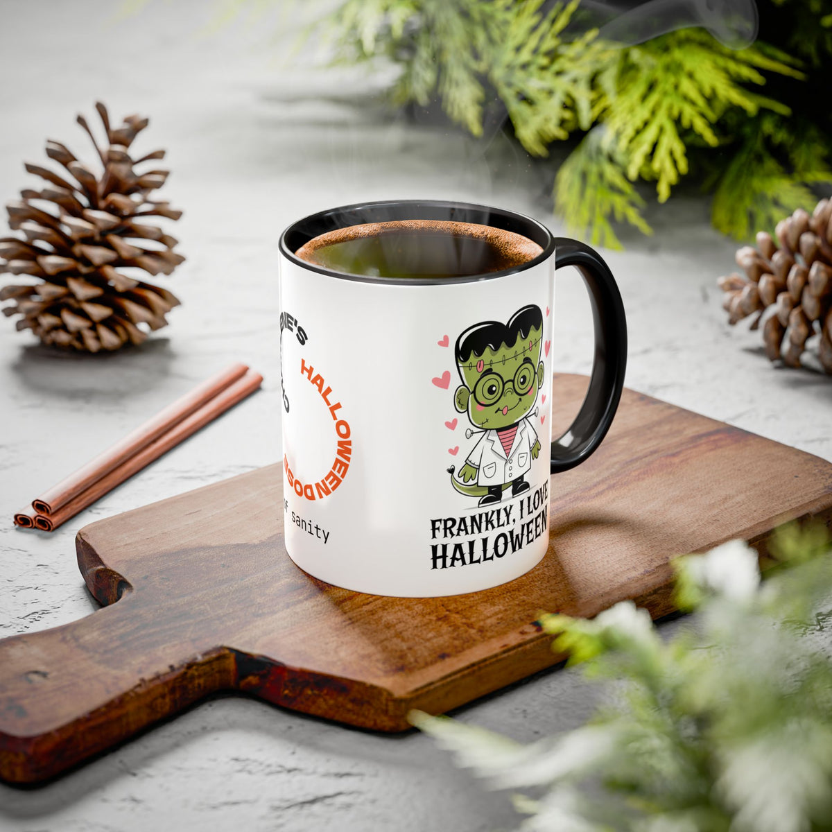 A white ceramic mug with a black handle and rim, filled with a hot beverage, placed on a wooden cutting board. The mug features a Frankenstein-themed Halloween graphic with the text 'FRANKLY I LOVE HALLOWEEN' and a cartoon of Frankenstein's monster.