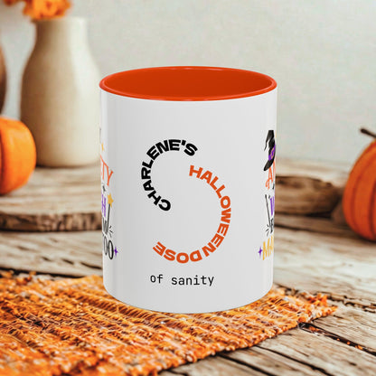 A white ceramic mug with a bright orange interior and printed Halloween-themed text and graphics, including 'CHARLIE'S HALLOWEEN DOSE of sanity', styled on a rustic wooden surface with pumpkins and a woven mat in the background.
