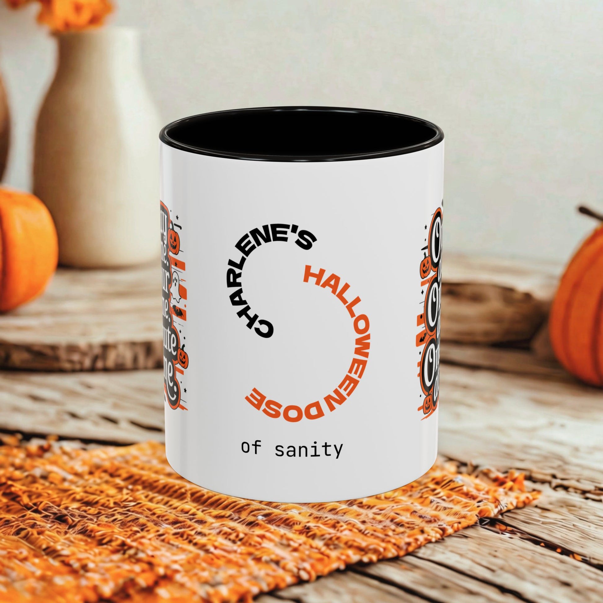 A white ceramic mug with a black interior and rim, printed with a Halloween-themed design featuring the text 'Charlene's Halloween Dose of sanity' and owl illustrations, set on a rustic wooden table with autumn decorations in the background.