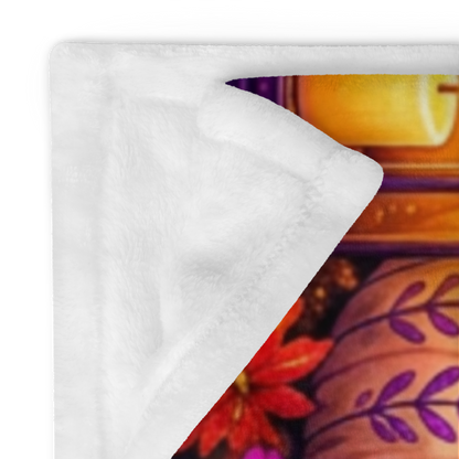 A colorful Halloween-themed blanket with the phrase “Treat Yourself Kindly” in large decorative lettering. The scene shows a smiling ghost in a witch hat holding a mug, surrounded by pumpkins, flowers, a house, candles, and autumn leaves on a purple background.