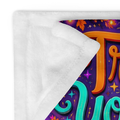 A colorful Halloween-themed blanket with the phrase “Treat Yourself Kindly” in large decorative lettering. The scene shows a smiling ghost in a witch hat holding a mug, surrounded by pumpkins, flowers, a house, candles, and autumn leaves on a purple background.