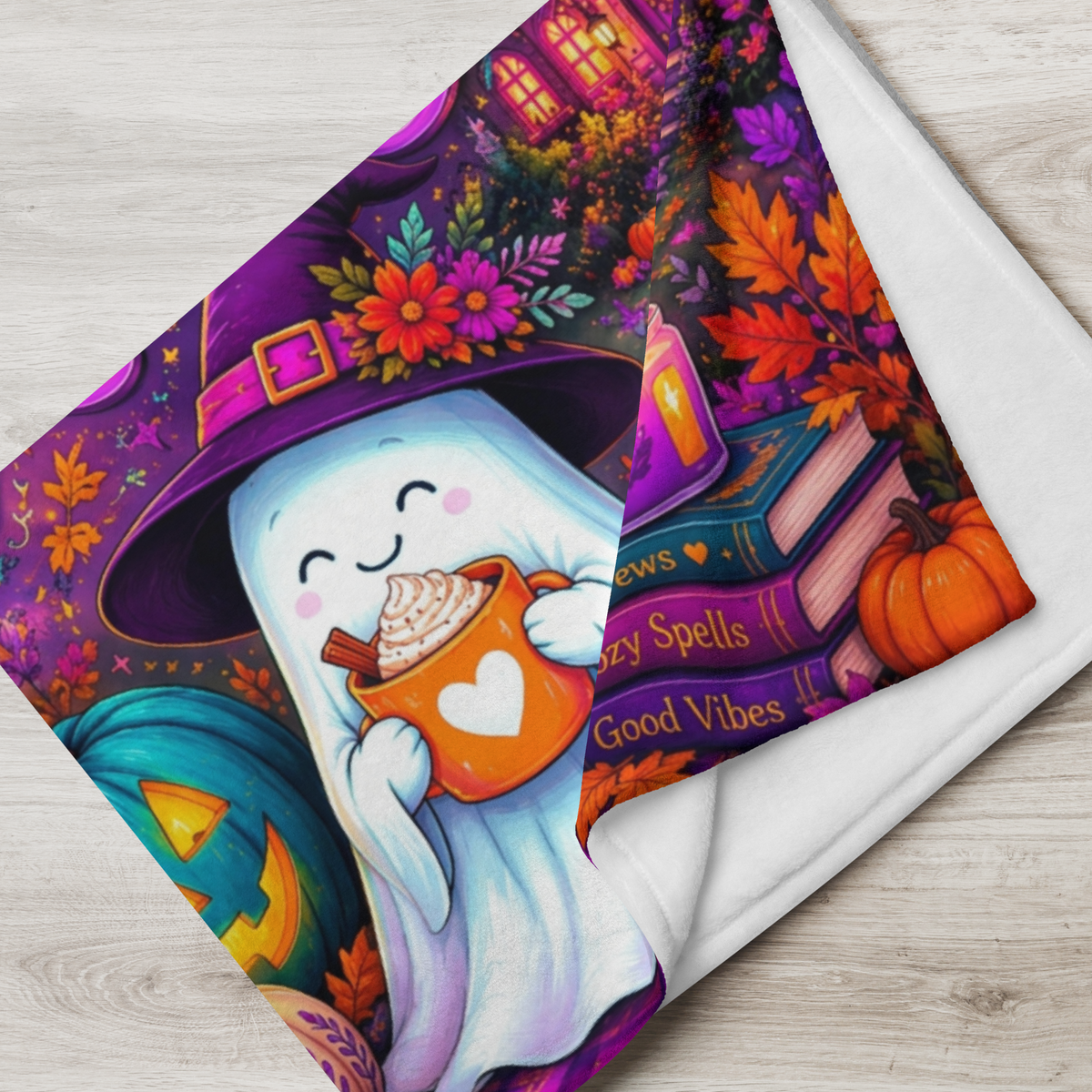 A colorful Halloween-themed blanket with the phrase “Treat Yourself Kindly” in large decorative lettering. The scene shows a smiling ghost in a witch hat holding a mug, surrounded by pumpkins, flowers, a house, candles, and autumn leaves on a purple background.