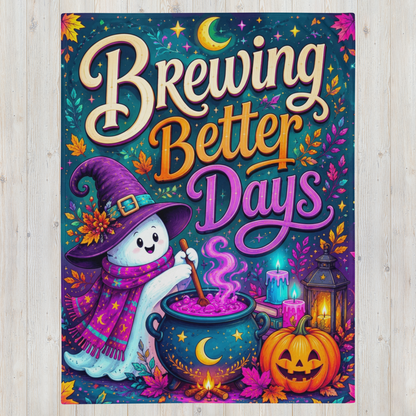 A colorful Halloween-themed art blanket featuring the text 'Brewing Better Days' in large decorative lettering, with a smiling ghost in a witch hat and scarf stirring a cauldron, alongside candles, a lantern, and a jack-o'-lantern on a light wood background.