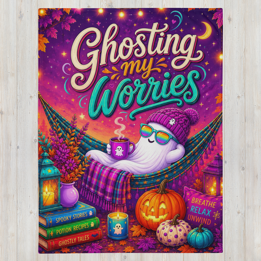 A colorful Halloween-themed art blanket with the phrase “Ghosting my Worries” in large decorative lettering. The scene shows a white ghost lounging in a hammock, surrounded by pumpkins, candles, books, and autumn leaves, with a purple and orange sky background.