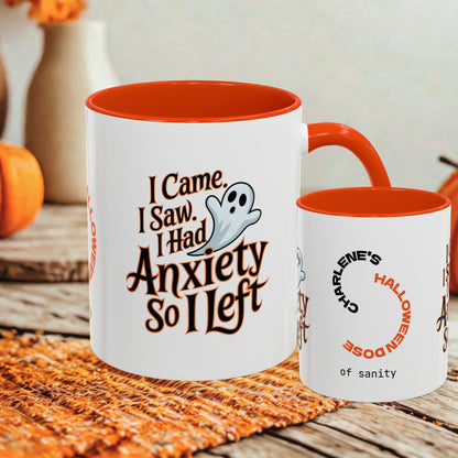 Two ceramic mugs with orange interiors and handles, displayed on a rustic wooden surface. The larger mug features the text 'I Came, I Saw, I Had Anxiety So I Left' with a small ghost illustration, while the smaller mug reads 'CHARLENE'S HALLOWEEN DOSE of sanity' in orange and black lettering.