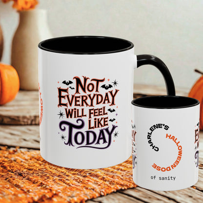 Two white ceramic mugs with black interiors and handles are shown on a rustic table with autumn decor. The larger mug features the phrase “Not Everyday Will Feel Like Today” in orange and black lettering with bats and stars.