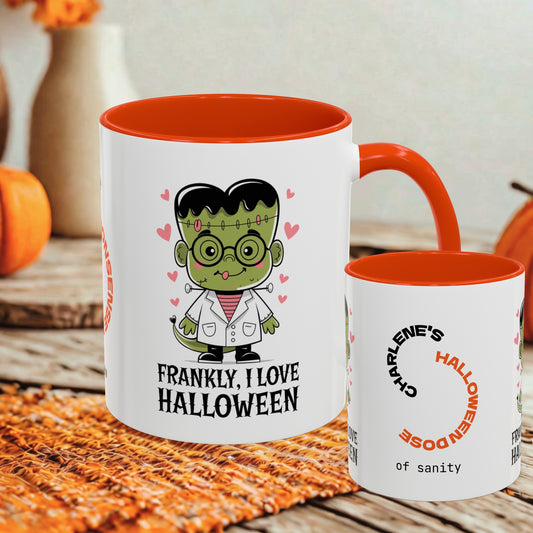 A white ceramic mug with a bright orange interior and handle, shown alongside a smaller matching mug. The larger mug features a cartoon Frankenstein character and the text 'FRANKLY, I LOVE HALLOWEEN.