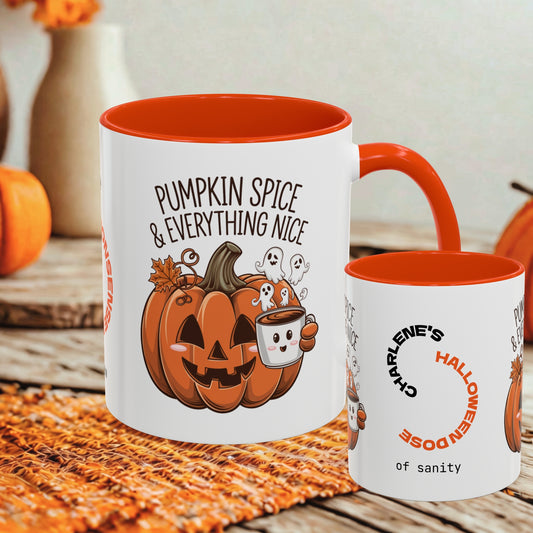 Two white ceramic mugs with orange interiors and handles, styled on a woven orange mat with autumn props. The larger mug reads 'PUMPKIN SPICE & EVERYTHING NICE' with a jack-o'-lantern, ghosts, and a coffee cup illustration.