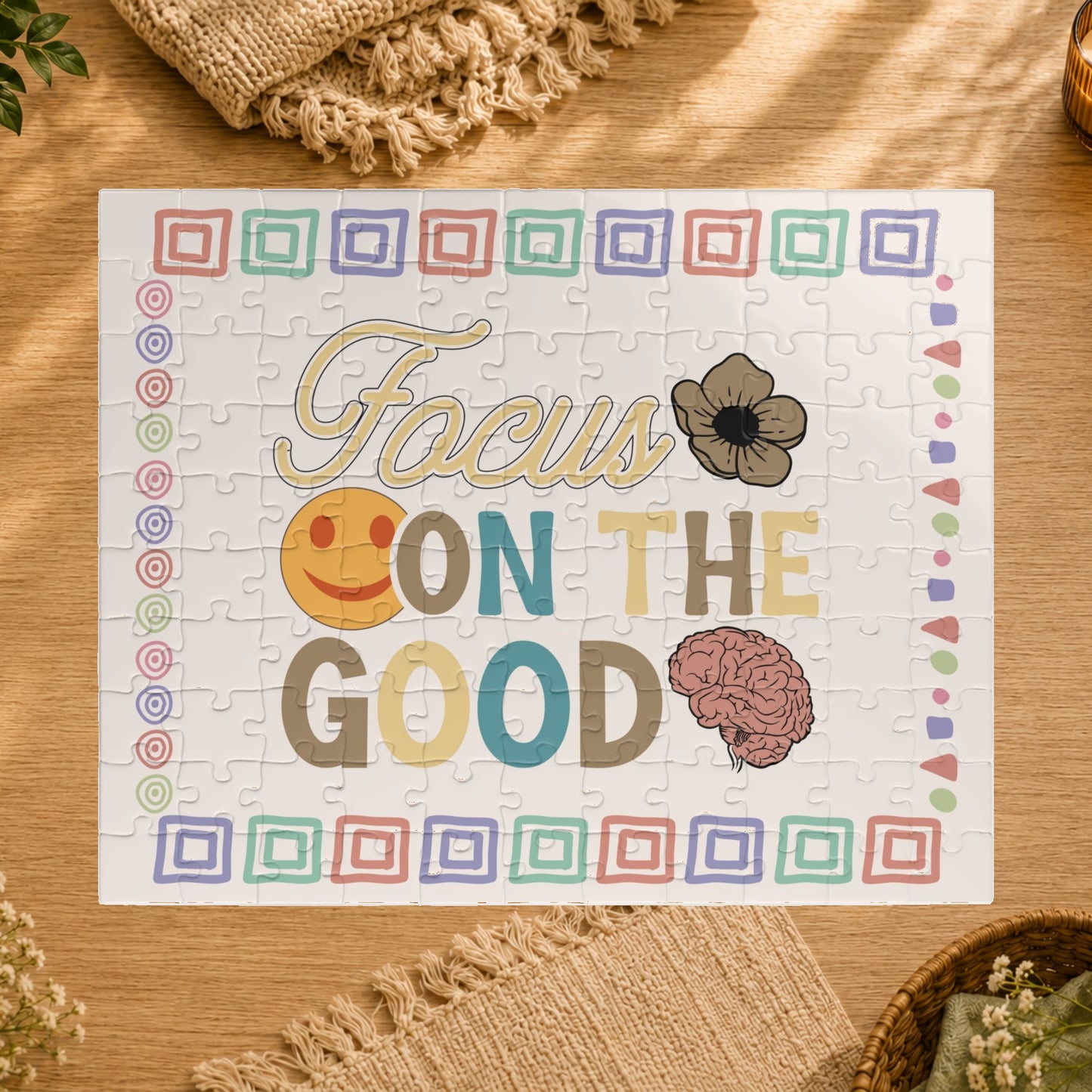 Jigsaw puzzle with 'Focus on the Good' text and smiley face, brain, and flower design on a white background.