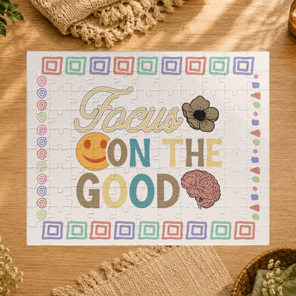 Jigsaw puzzle with 'Focus on the Good' text and smiley face, brain, and flower design on a white background.