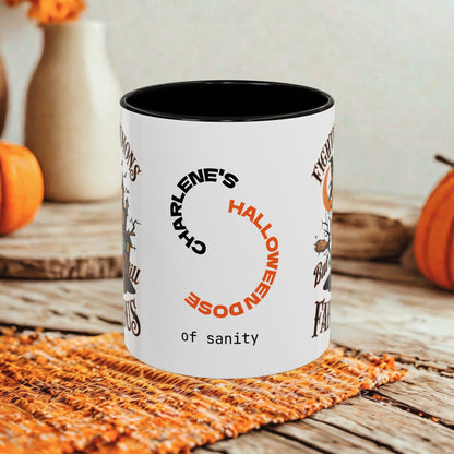 A white ceramic mug with a black interior, printed with Halloween-themed text and graphics including 'Charlene's Halloween Dose of sanity', shown on a rustic wooden surface with pumpkins and a woven mat in the background.