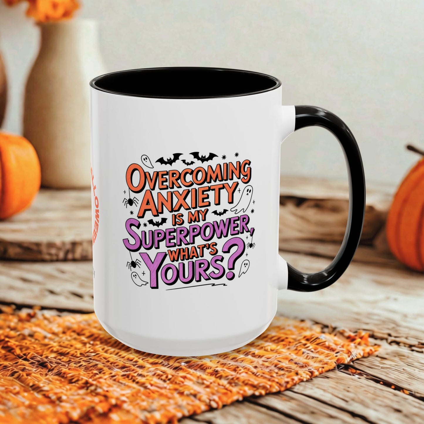 A white ceramic mug with a black handle and interior, featuring the printed text 'Overcoming Anxiety is my Superpower, what's yours?' in orange and purple lettering. The mug is styled on a rustic wooden surface with a woven orange placemat and blurred orange pumpkins in the background.