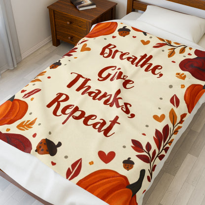 Cozy blanket with “Breathe, Give Thanks, Repeat,” autumn mindfulness theme in orange and gold hues.