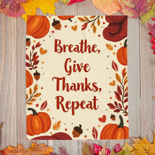 Cozy blanket with “Breathe, Give Thanks, Repeat,” autumn mindfulness theme in orange and gold hues.