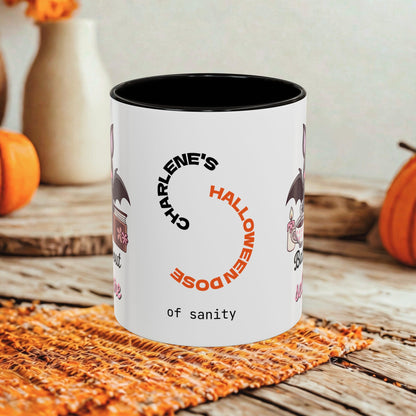 A white ceramic mug with a black interior, printed with a Halloween-themed design featuring the text 'CHARLENE'S HALLOWEEN DOSE of sanity' in black and orange, styled on a rustic wooden table with pumpkins in the background.