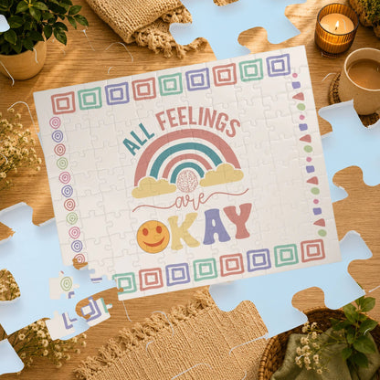 Puzzle with 'All Feelings Are Okay' message on a wooden table with decorative items.